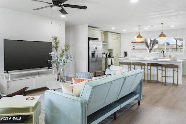 living room featuring ceiling fan, sink, and light hardwood / wood-style flooring