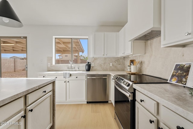 kitchen featuring white cabinets, sink, light hardwood / wood-style floors, custom range hood, and stainless steel appliances