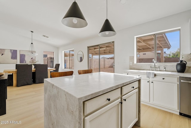 kitchen with dishwasher, a kitchen island, hanging light fixtures, and vaulted ceiling