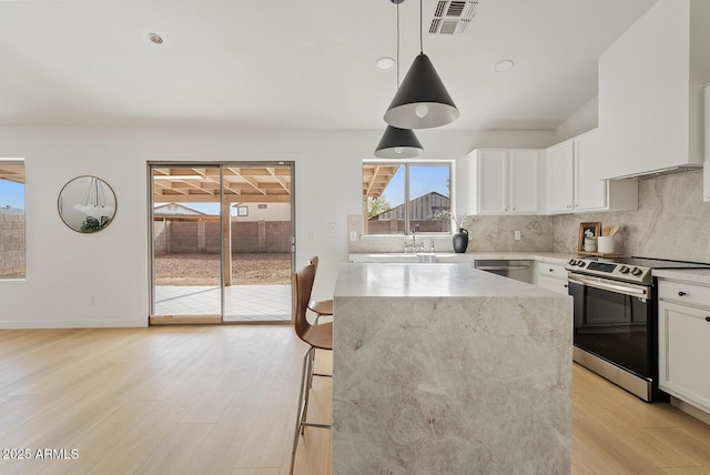 kitchen with hanging light fixtures, white cabinets, stainless steel appliances, and a kitchen island