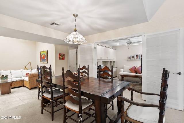 carpeted dining area featuring ceiling fan with notable chandelier