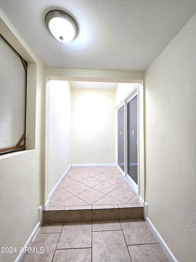 corridor with a textured ceiling and light tile patterned floors