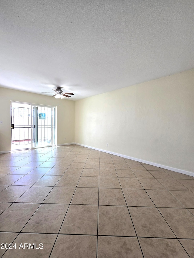 spare room with ceiling fan, a textured ceiling, and light tile patterned floors