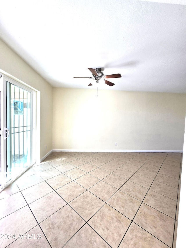 tiled spare room with ceiling fan