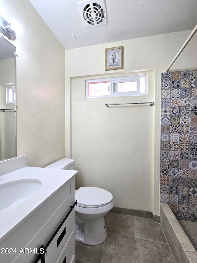 bathroom with vanity, toilet, tile patterned floors, and a shower