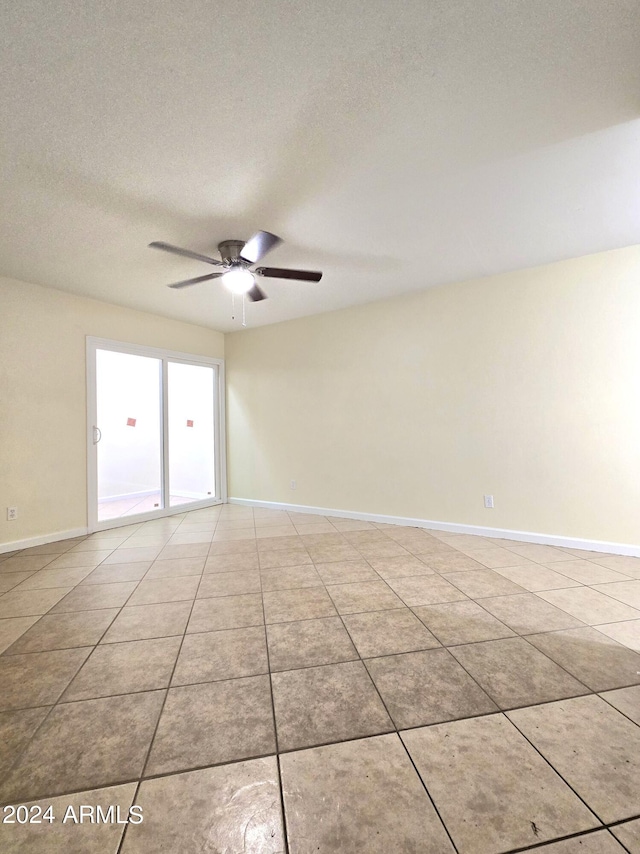 empty room with a textured ceiling, light tile patterned floors, and ceiling fan