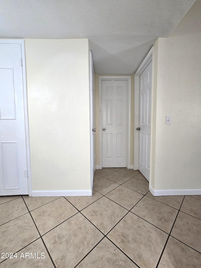 corridor featuring a textured ceiling and light tile patterned floors