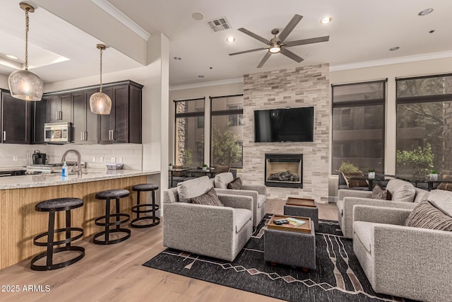 4805 N Woodmere Fairway Unit 1002, Scottsdale, AZ 85251 - living room with light wood finished floors, ceiling fan, crown molding, recessed lighting, and a tile fireplace