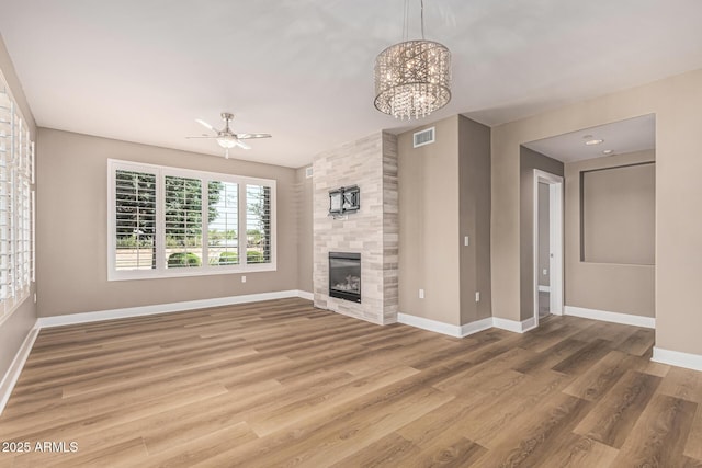 4805 N Woodmere Fairway Unit 1002, Scottsdale, AZ 85251 - unfurnished living room with light wood finished floors, a fireplace, a ceiling fan, and a chandelier