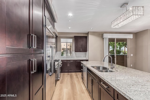 4805 N Woodmere Fairway Unit 1002, Scottsdale, AZ 85251 - kitchen featuring high quality appliances, light wood finished floors, light stone countertops, dark brown cabinets, and hanging light fixtures