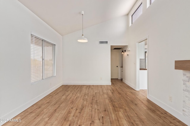 unfurnished dining area featuring high vaulted ceiling, light wood-style floors, and baseboards