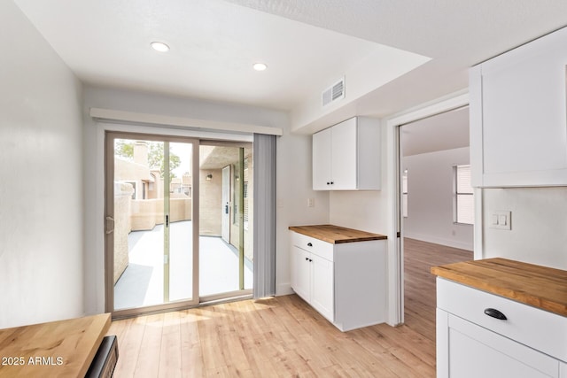 kitchen featuring butcher block countertops, white cabinets, light wood finished floors, and recessed lighting