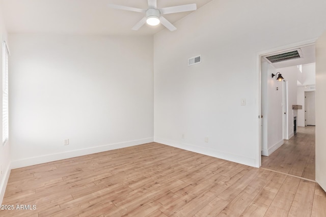 empty room with light wood-type flooring, a ceiling fan, and baseboards