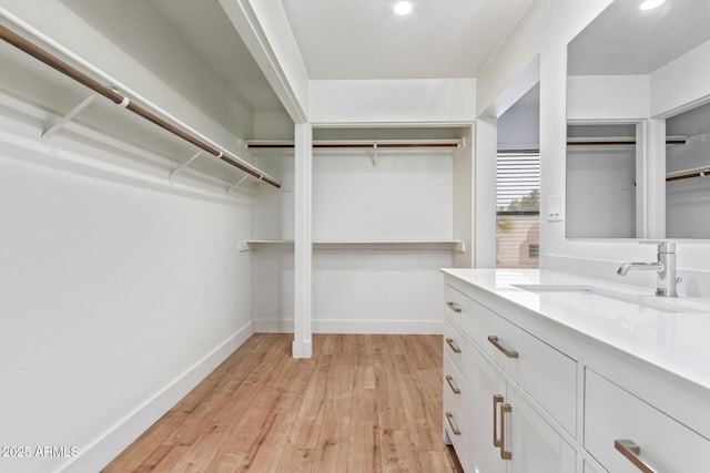 spacious closet featuring a sink and light wood-style floors
