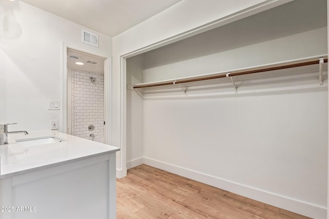 washroom with a sink, light wood-style floors, and baseboards
