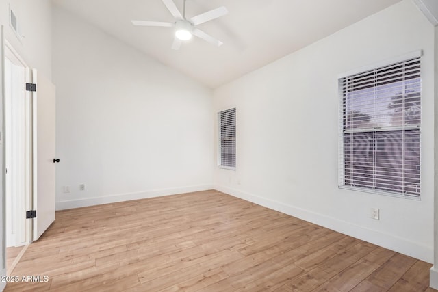 empty room featuring a ceiling fan, vaulted ceiling, light wood-style flooring, and baseboards