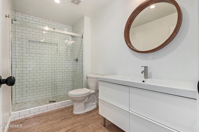 full bathroom with toilet, a stall shower, wood finished floors, vanity, and recessed lighting