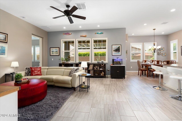 living room featuring ceiling fan with notable chandelier