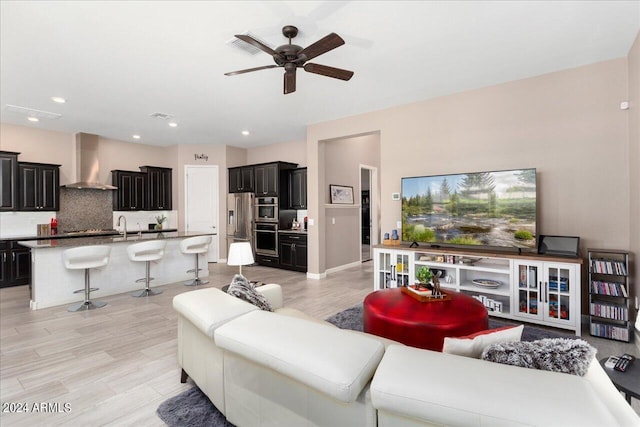 living room with ceiling fan, light hardwood / wood-style flooring, and sink