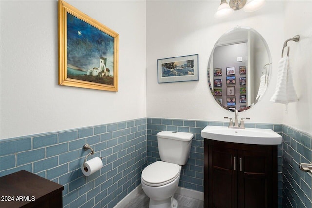 bathroom with vanity, toilet, and tile walls