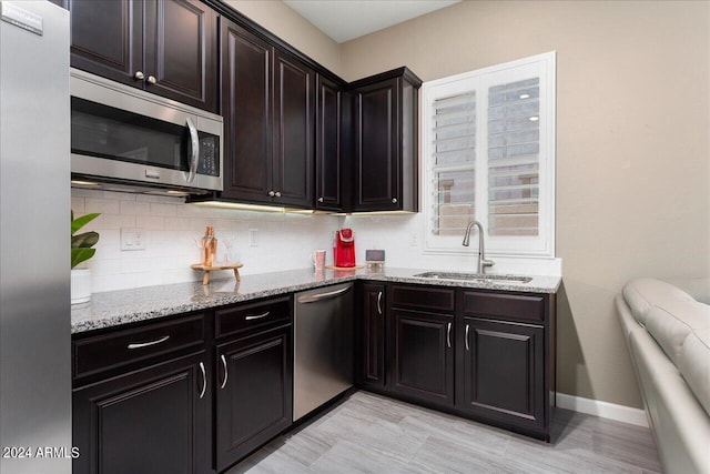 kitchen with light stone counters, sink, dark brown cabinets, and stainless steel appliances