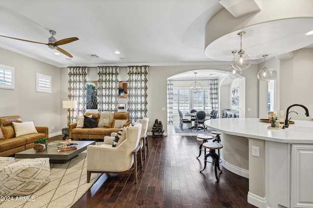 living room with plenty of natural light, dark hardwood / wood-style floors, crown molding, and ceiling fan with notable chandelier