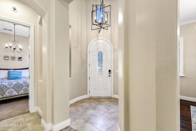 foyer entrance with a chandelier, light wood-type flooring, and ornamental molding