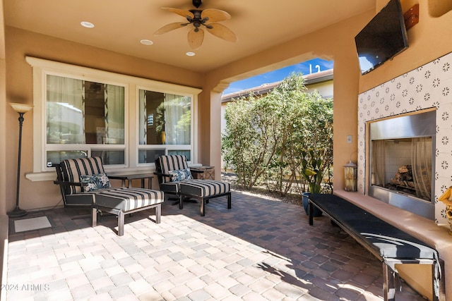 view of patio featuring ceiling fan and an outdoor fireplace