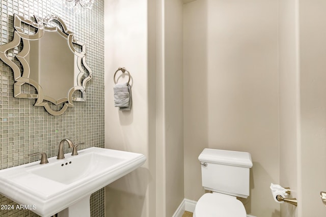 bathroom featuring decorative backsplash, toilet, and sink