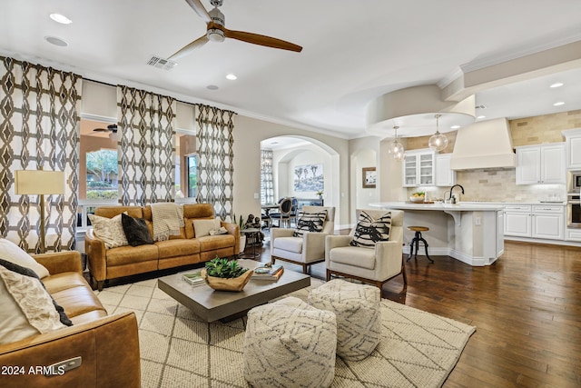 living room with ceiling fan, light wood-type flooring, and ornamental molding