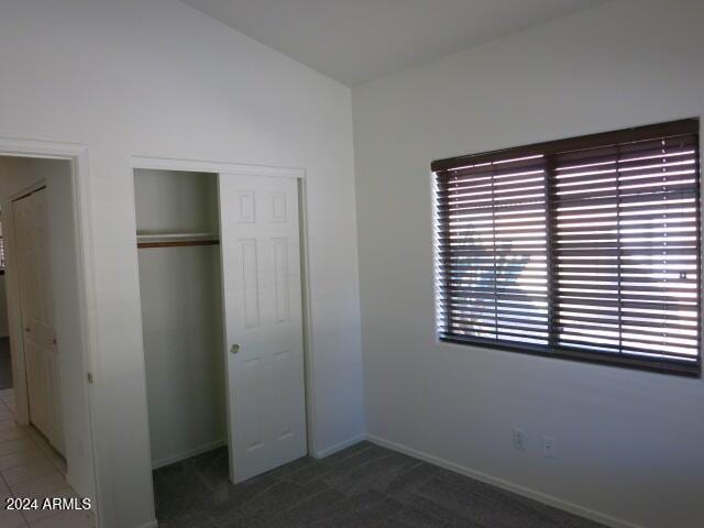 unfurnished bedroom with a closet and dark colored carpet