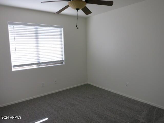 empty room featuring ceiling fan and dark colored carpet