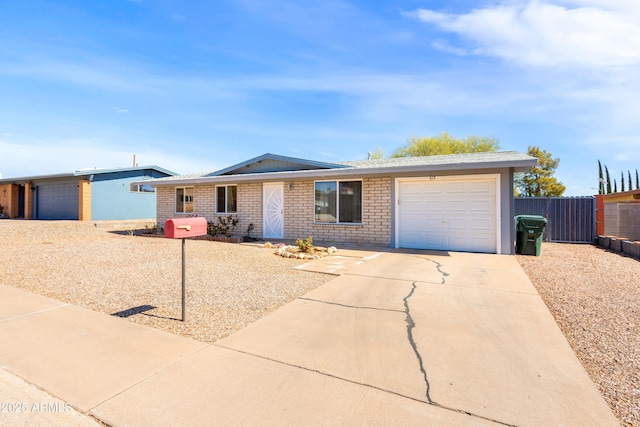 ranch-style house with concrete driveway, an attached garage, fence, and brick siding