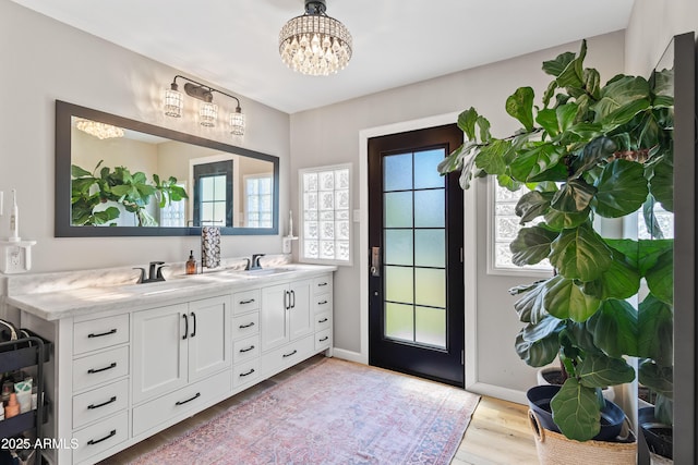 full bathroom featuring a chandelier, wood finished floors, double vanity, and baseboards