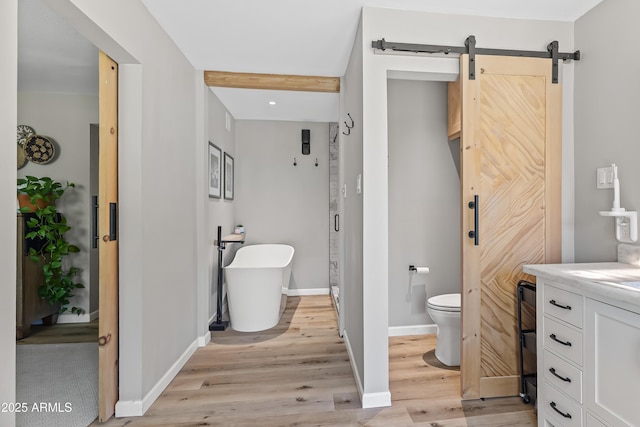 full bath with wood finished floors, baseboards, a soaking tub, toilet, and vanity