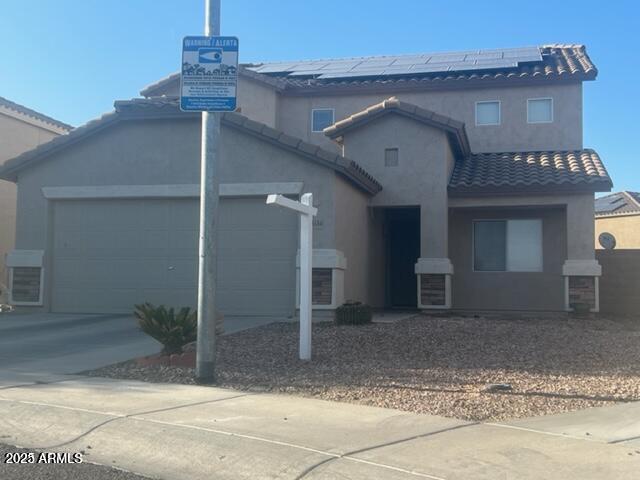 view of front of property featuring a garage and solar panels