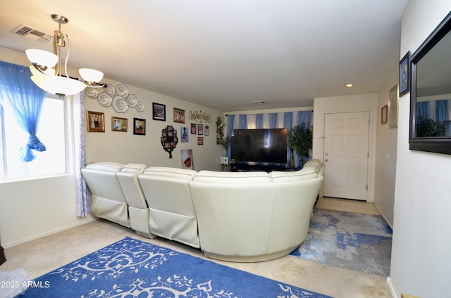 carpeted living room featuring an inviting chandelier