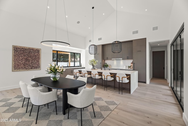 dining room with baseboards, visible vents, and light wood finished floors