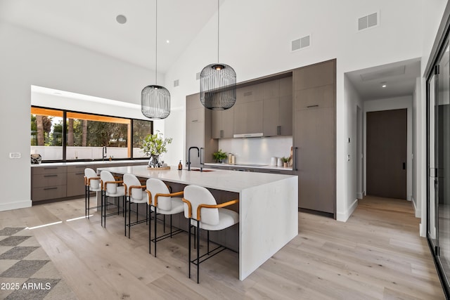 kitchen with decorative light fixtures, visible vents, a kitchen bar, and modern cabinets