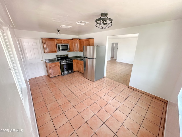 2928 N 37th Ave, Phoenix, AZ 85019 - kitchen featuring stainless steel appliances, dark countertops, baseboards, brown cabinetry, and light tile patterned floors