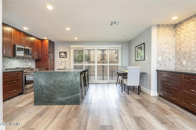 kitchen featuring light wood-type flooring, dark countertops, visible vents, and stainless steel appliances