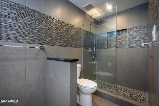 full bathroom featuring toilet, tile patterned flooring, a walk in shower, and visible vents