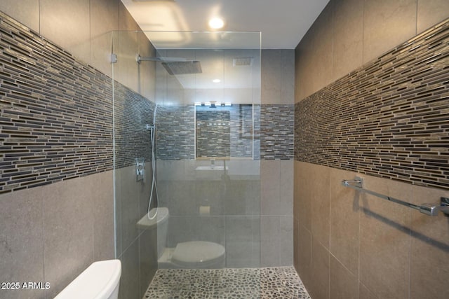 bathroom featuring a tile shower and toilet