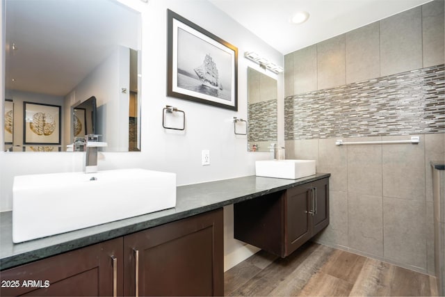 bathroom with double vanity, wood finished floors, a sink, and recessed lighting