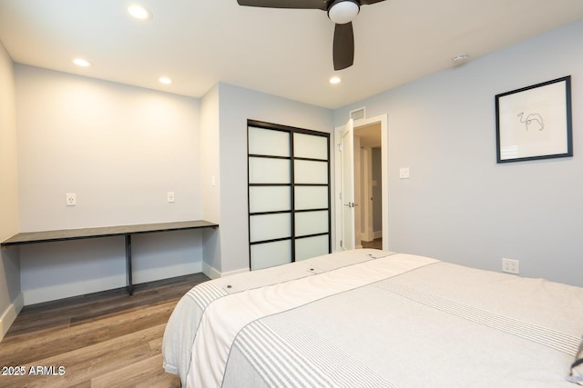 bedroom featuring baseboards, visible vents, wood finished floors, built in desk, and recessed lighting