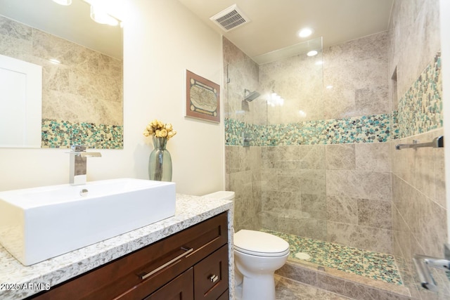 full bathroom with visible vents, vanity, toilet, and a walk in shower