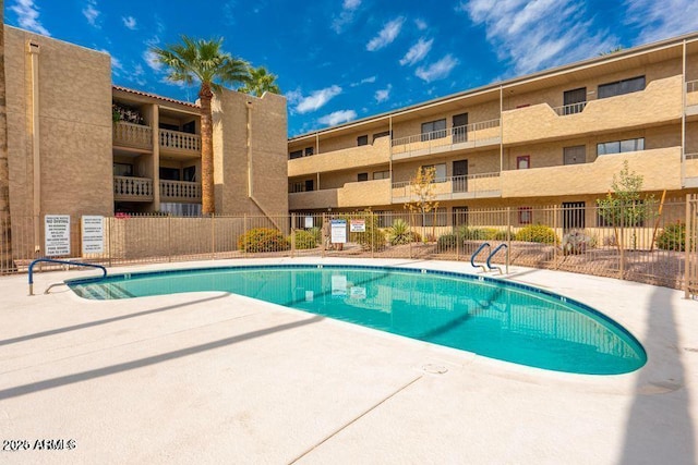 community pool with a patio area and fence