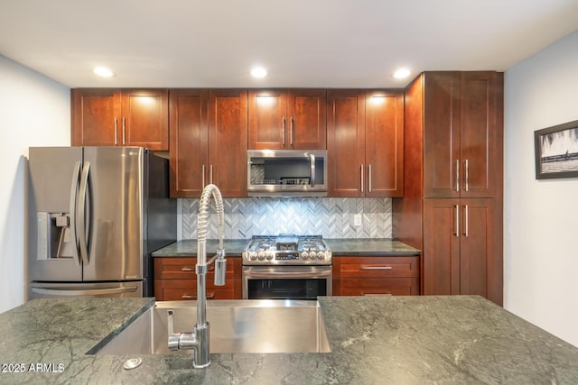 kitchen featuring recessed lighting, backsplash, appliances with stainless steel finishes, dark brown cabinets, and dark stone counters