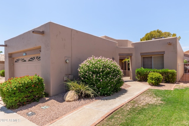 pueblo-style home with a garage and a front lawn