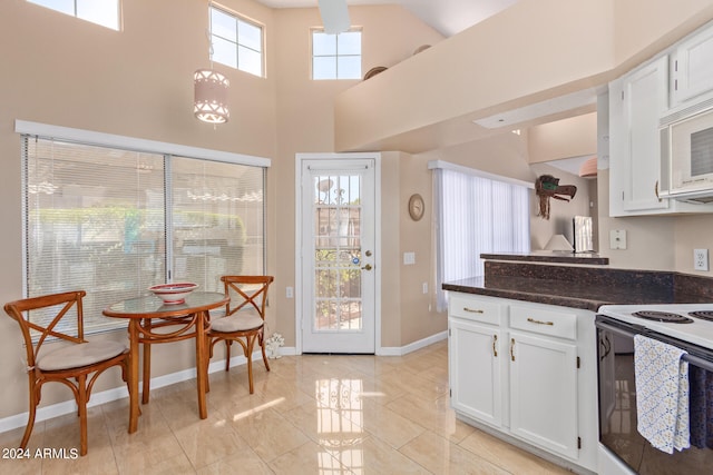 kitchen featuring white appliances, a high ceiling, decorative light fixtures, and white cabinets